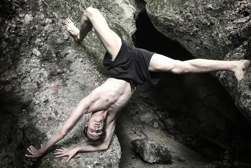 Samuli Emery kalliolla käsillä seisonnassa, nojaten jalat harallaan takana olevaan kallioon.