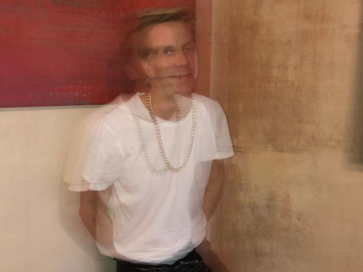 Simo Vassinen in an out of focus picture, wearing a white shirt and black trousers