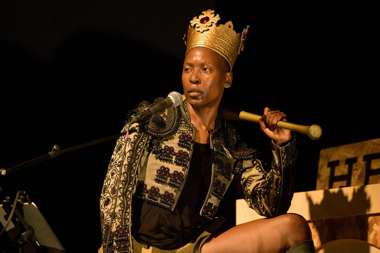 A black person wearing a crown, holding a golden baseball bat on their sholder.