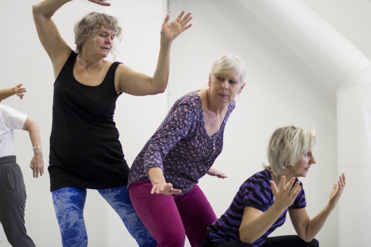 Three seniors in a diagonal dancing in different levels, one on the floor, one on the middle and one standing