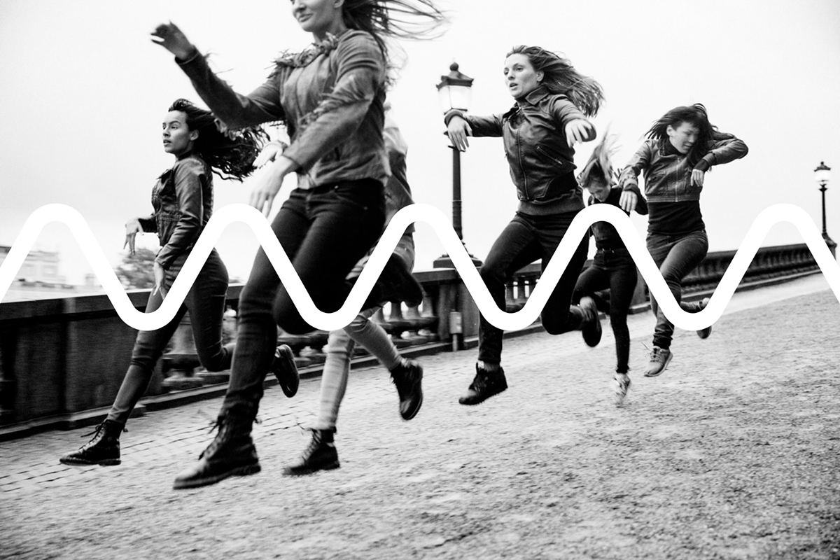 A black-and-white photo of a group of assumed females, galloping on the street.