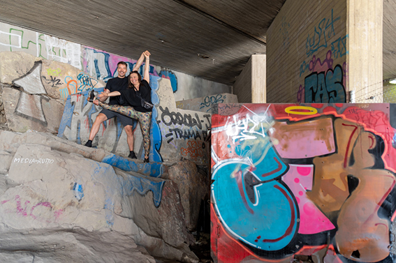 Two people standing under a concrete bridge