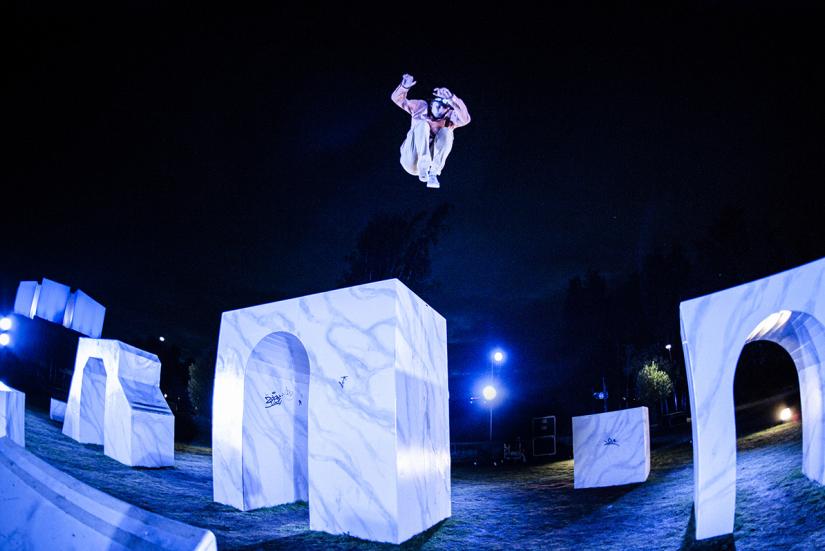 A performer is jumping high from The Wall. The photo is taken in the evening.