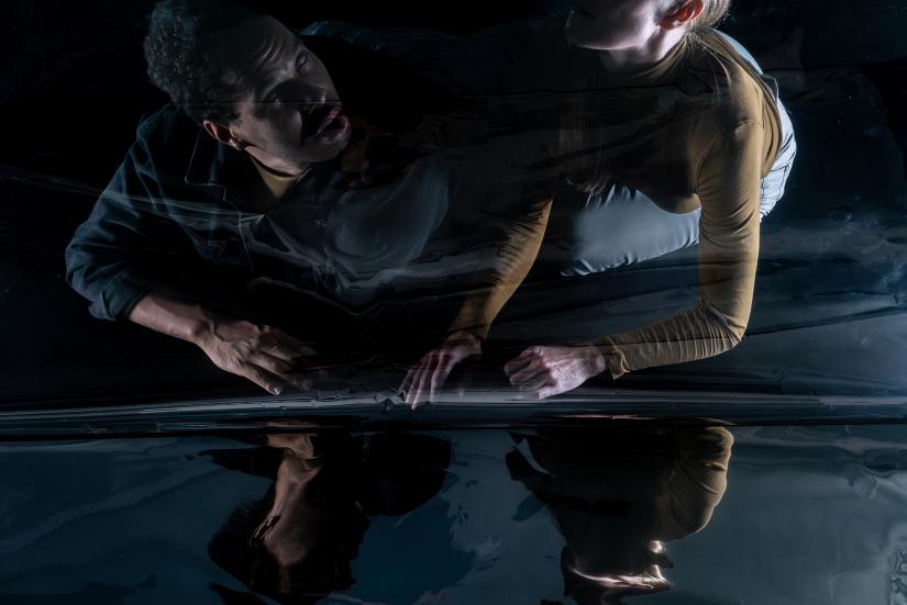 Two people are sitting next to a reflecting surface.