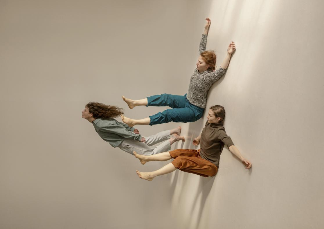Kolme tanssijaa roikkuu seinästä