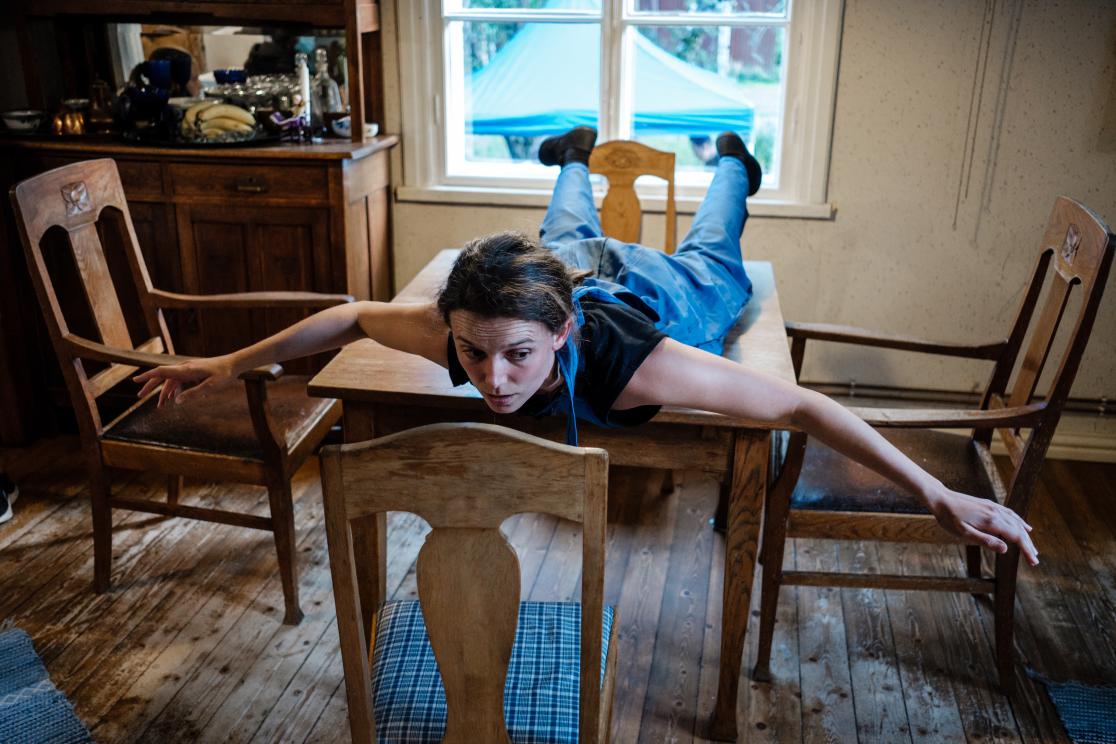 Tanssija makaa pienen keittiönpöydän päällä vatsallaan