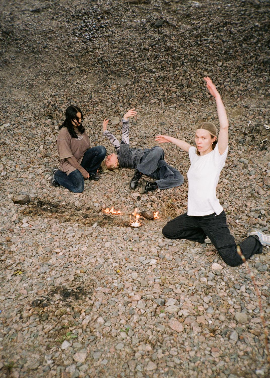 Three people are situated on top of a rocky surface.