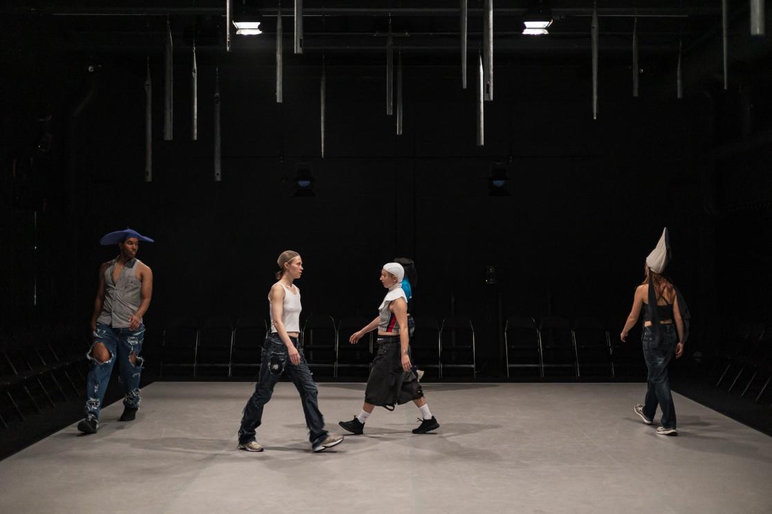 Kuva esityksestä. Neljä esiintyjää kävelee näyttämöllä.