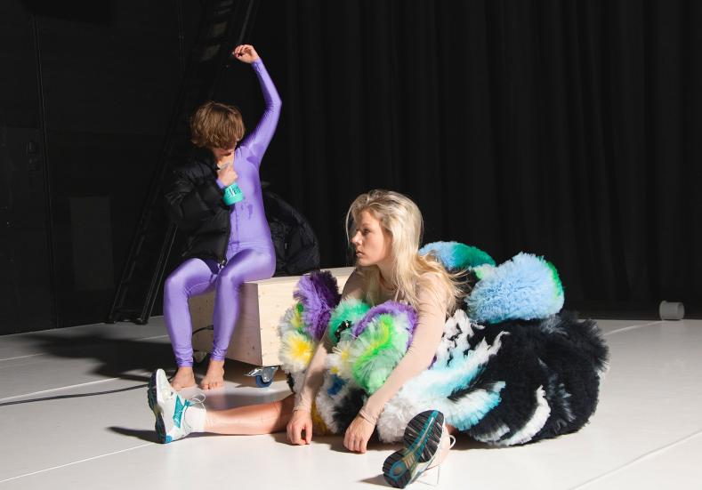 Two performers. One is sitting on a box. The other one on the floor.