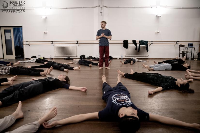 Lewis Cooke in the middle of dancers laying on the floor
