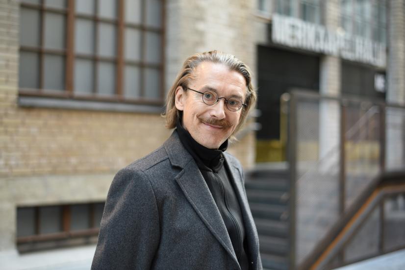 Photo: Elina Keckman Jyrki Karttunen smiling in front of a grey building.