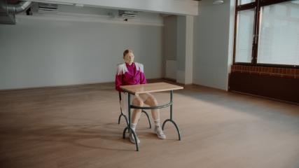 Still from the film. Kielo is sitting by a school desk.
