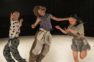 Three dancers jumping in the air loosely.