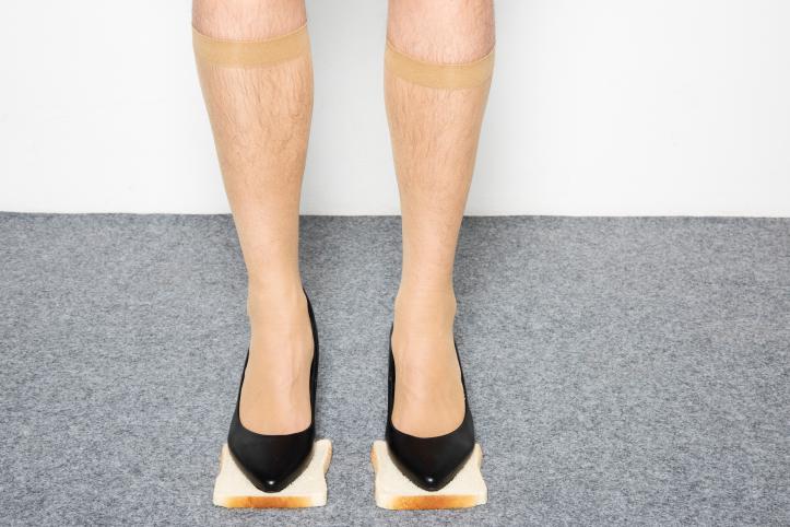Kuvassa jalat, joissa mustat korkokengät. Henkilö seisoo kahden paahtoleipäviipaleen päällä