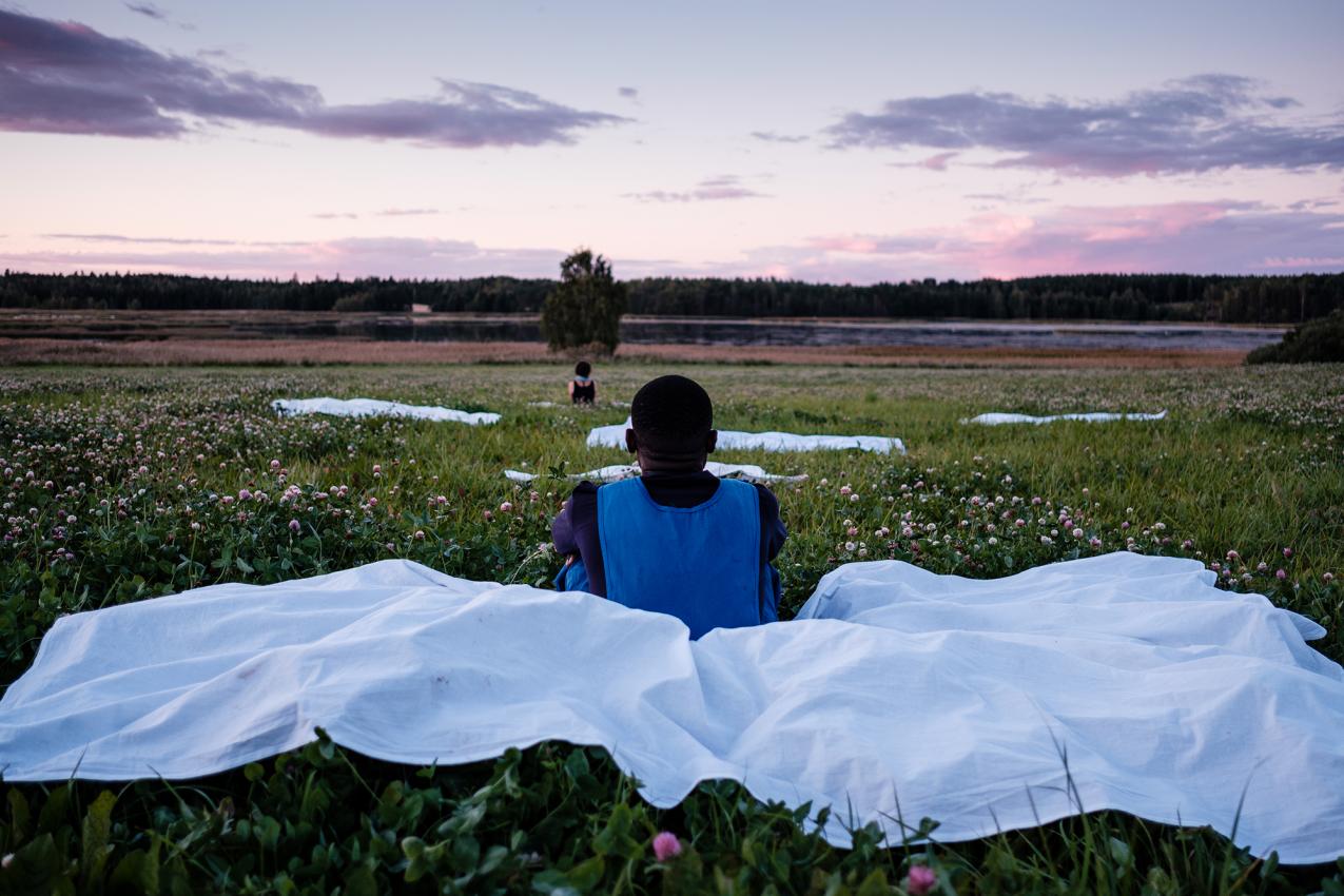 Two people sitting in a field, and looking at the sunset.