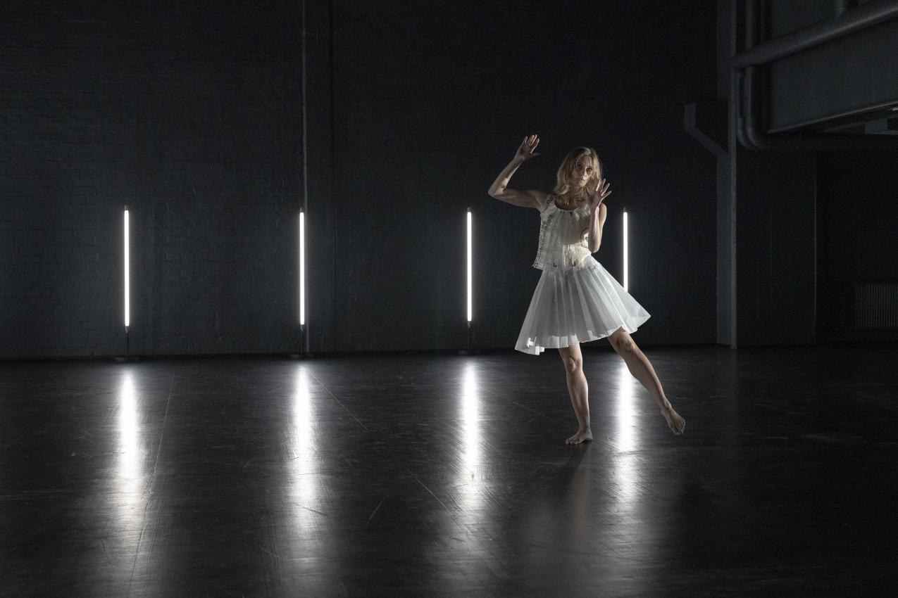 Dancer in a white skirt, with their back to the camera.