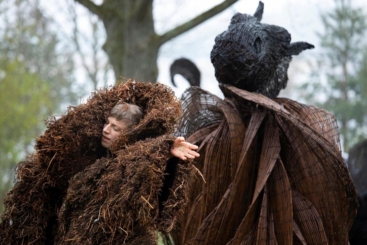 A human inside a huge spherical formation made out of natural materials.