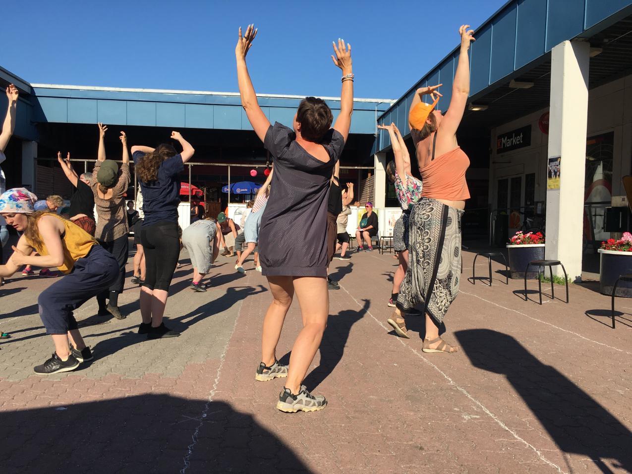 A group of people dancing outside in the summertime.