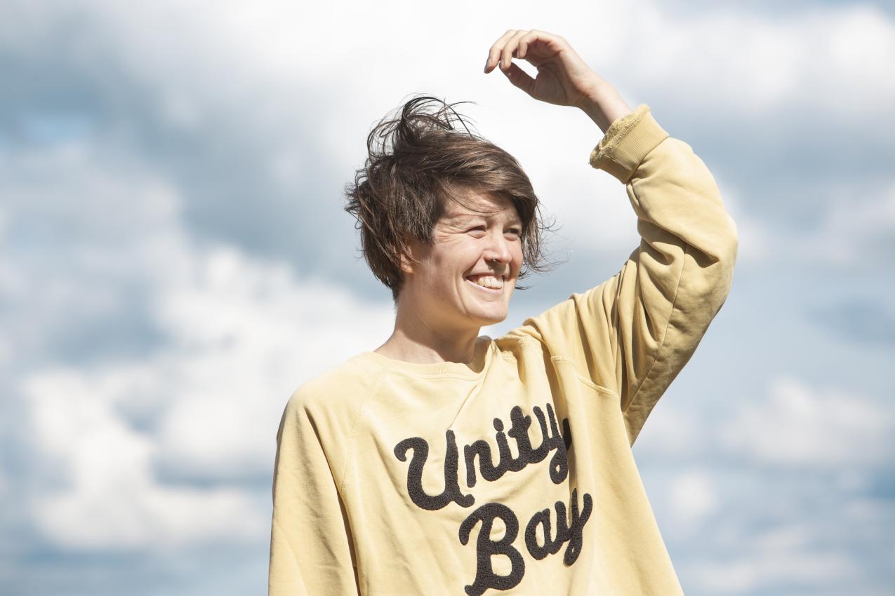 Person, one hand thrown up, with sky and clouds in the background