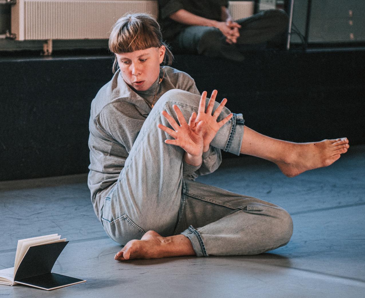 Anna Mustonen sitting down in a spiraly position looking at a book