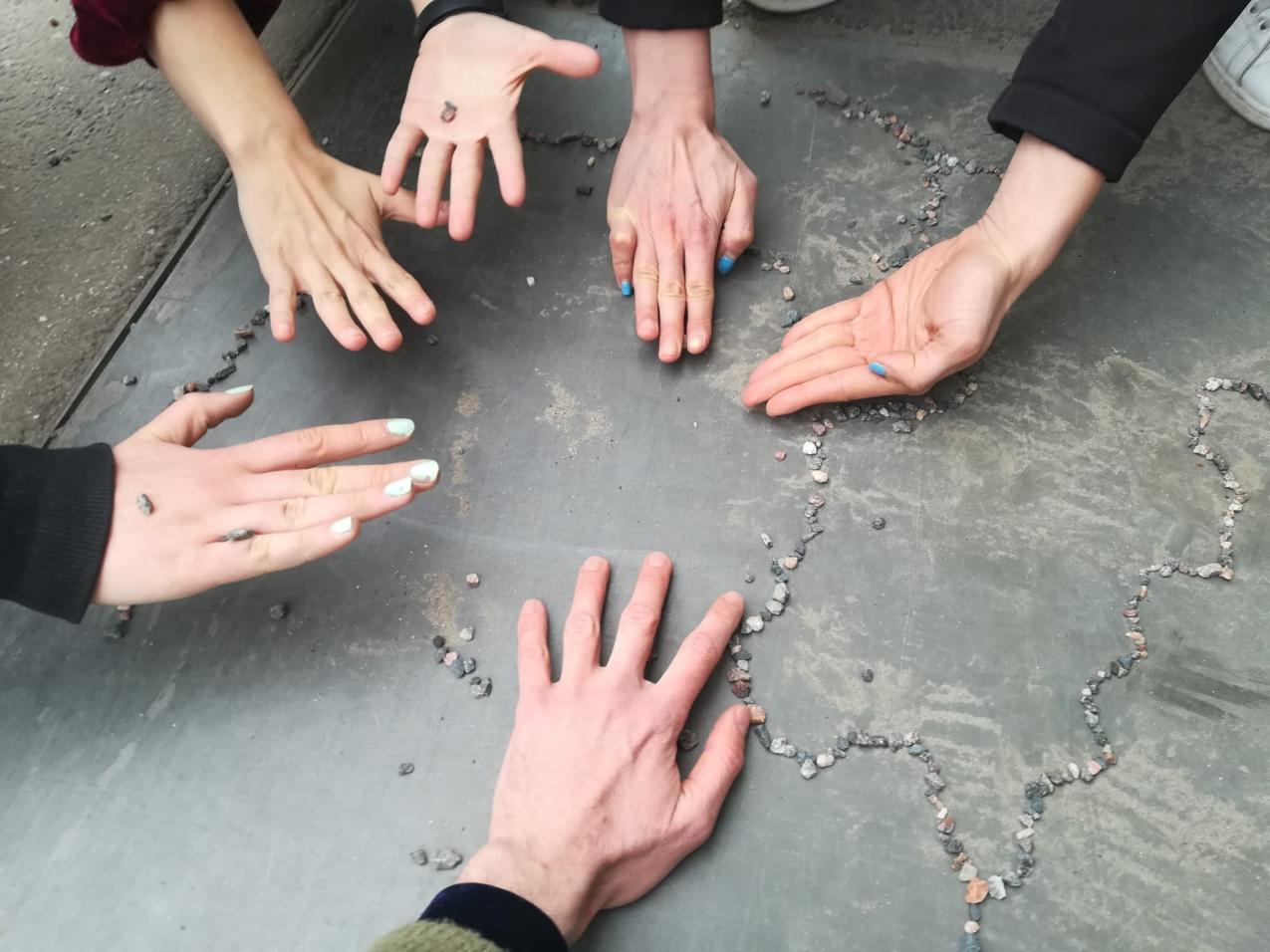 Six hands close to the floor and close to each other in a circle shape
