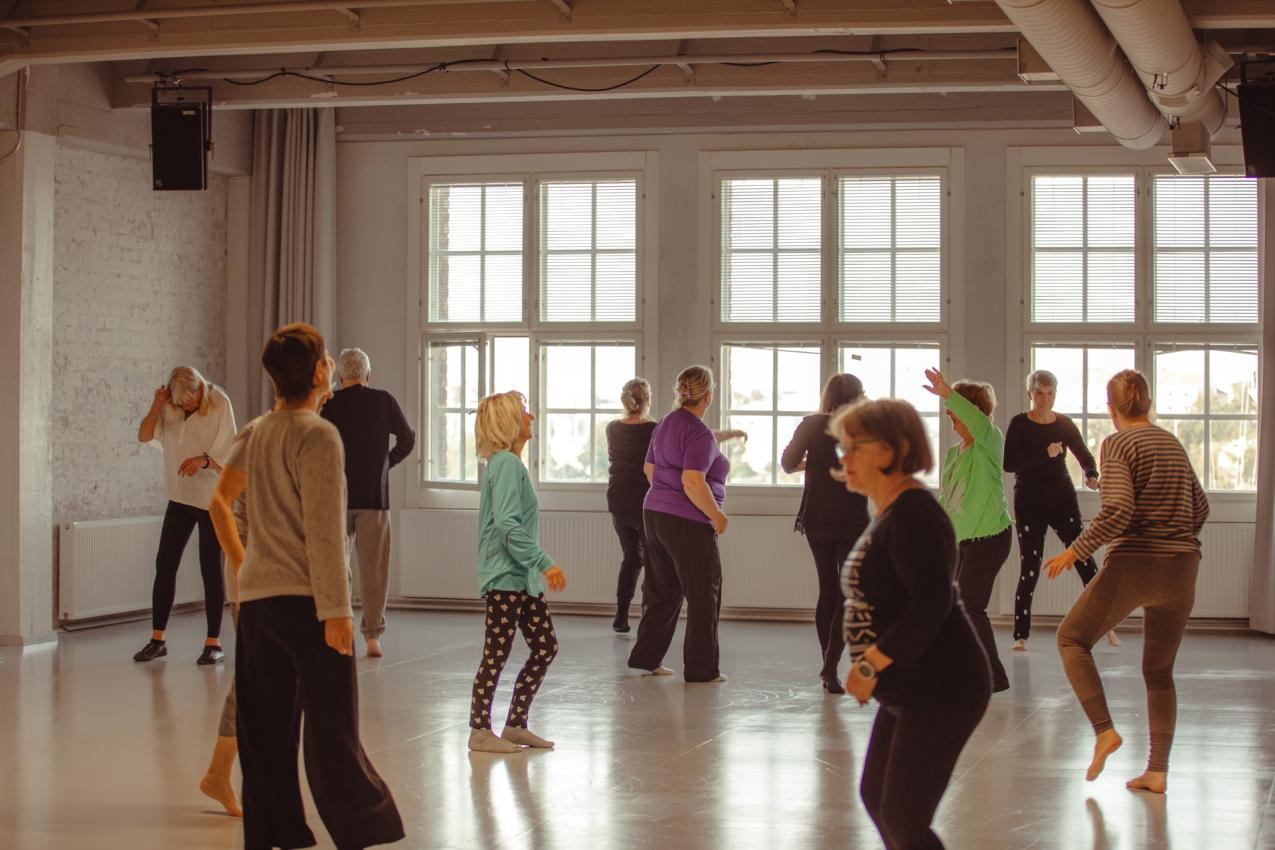 A group of elderly people dancing in a white studio