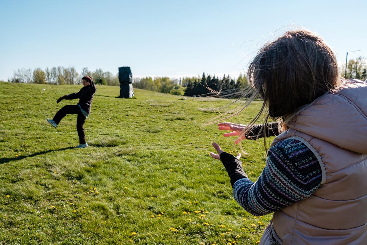 Two people on a grassy field. One of them is a lot closer to the camera than the other