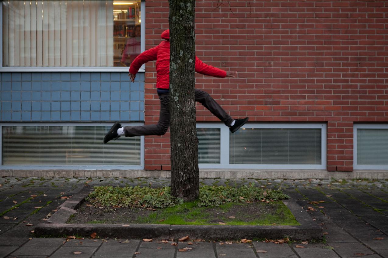 A person in mid-flight of a jump. Their torso is hidden behind a tree trunk.