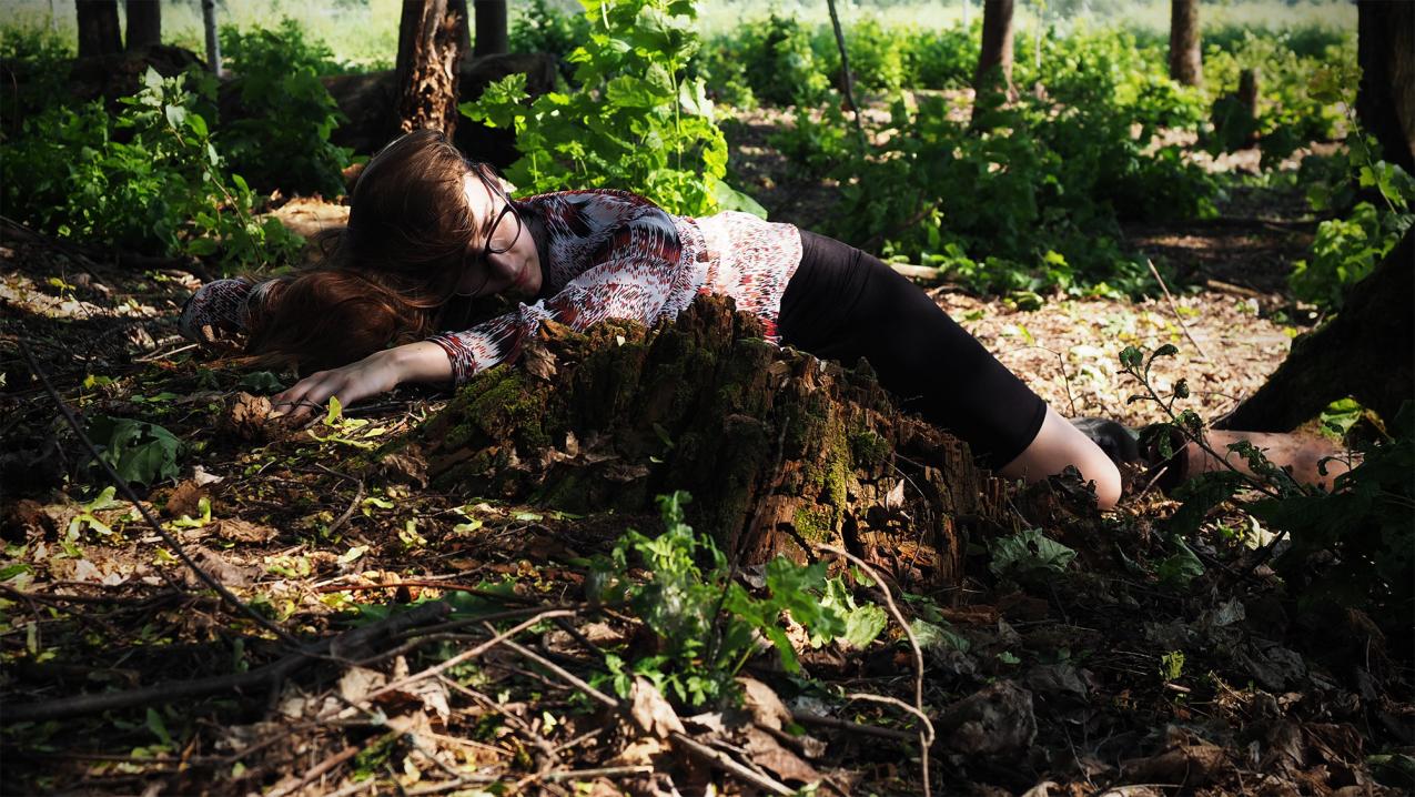 A showdy forrest. One perso is lying on the ground.