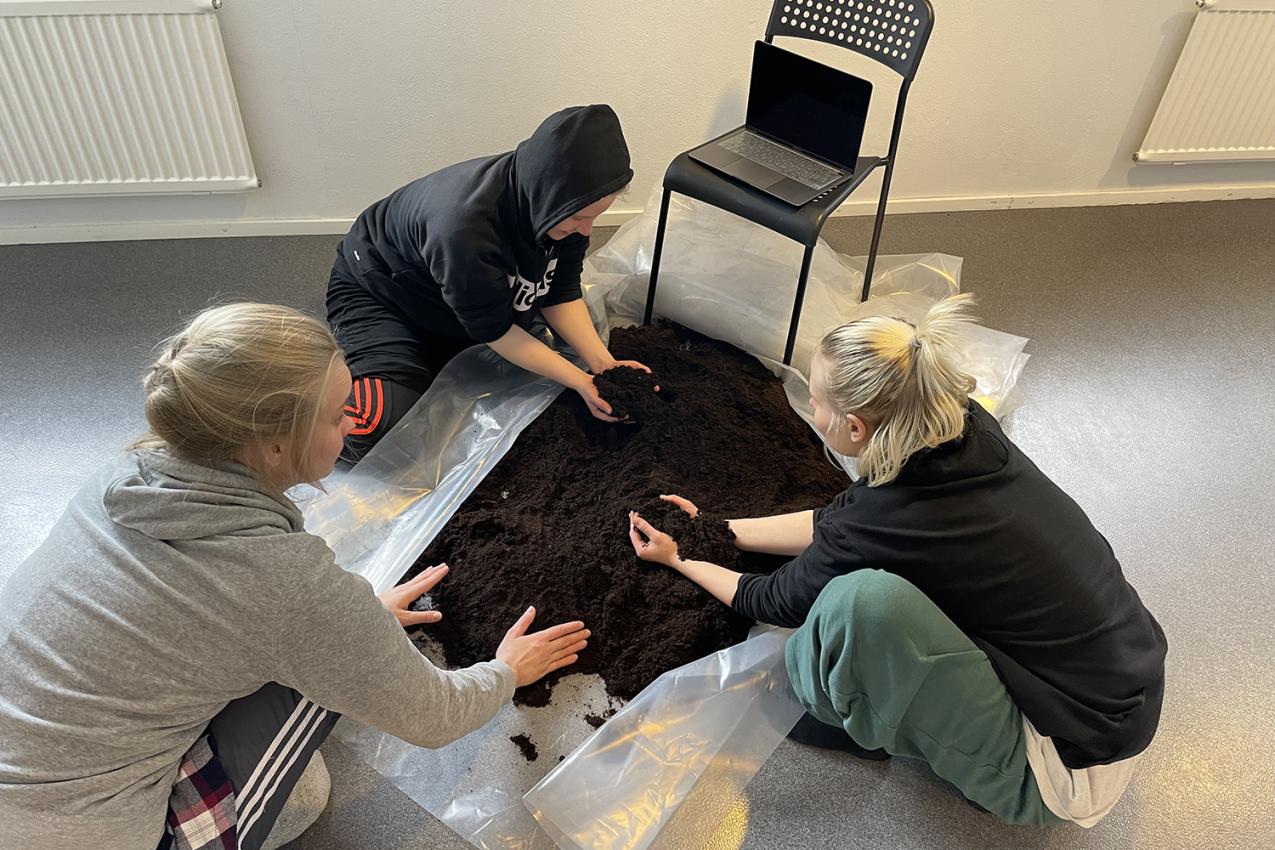 Three performers are handling dirt.