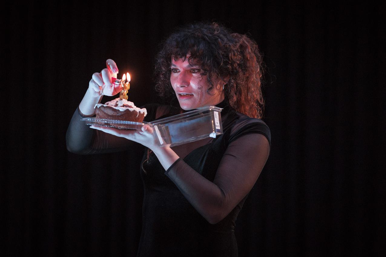 Henkilö sytyttää pienen kakun päällä olevan pienen kynttilän.