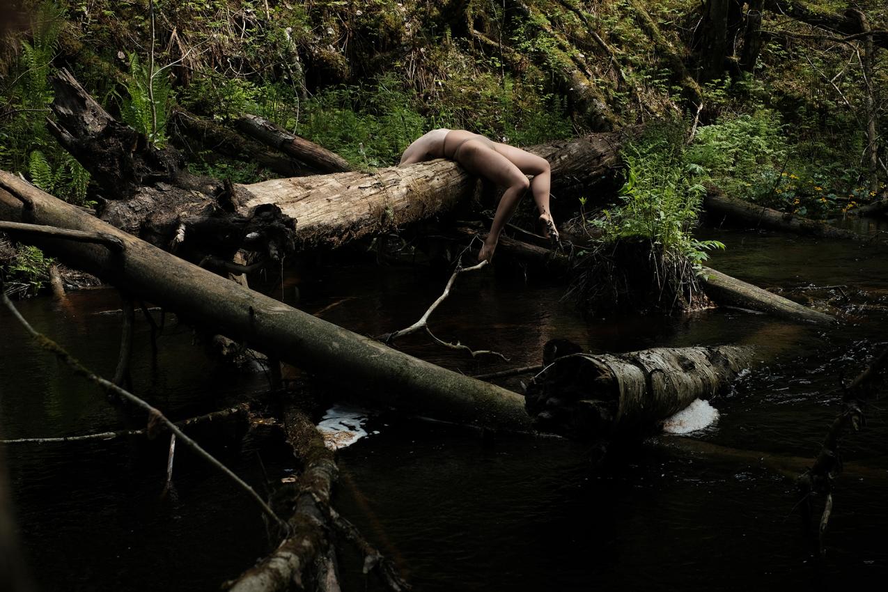 A person is lying on their back on a tree trunk. We can't see their face.