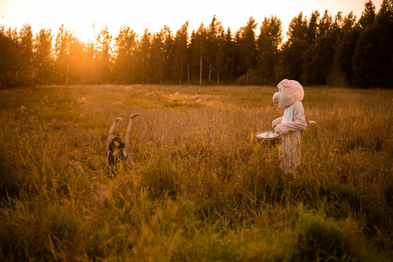 A dancer and a performer dressed as a pig in a field.