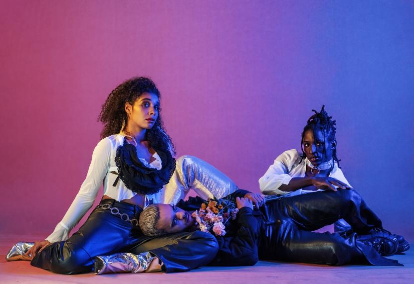 Three performers sit on the floor