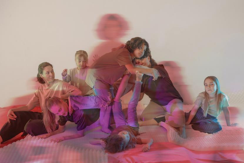 A group of children and adults sitting on the ground.