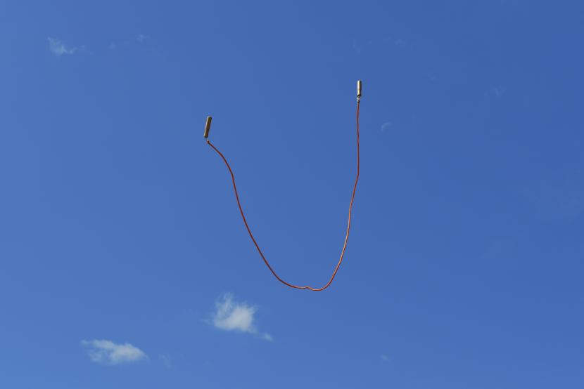 A skipping rope is hanging in the air. The sky is very blue.