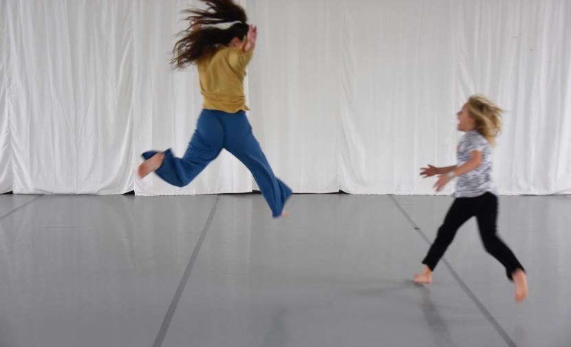 Two people jumping around in a room delimited with white curtains