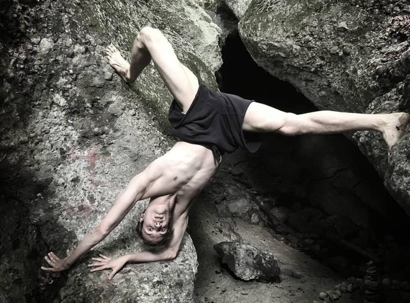 Samuli Emery on a big rock upsidedown in a handstand, leaning to the rock.