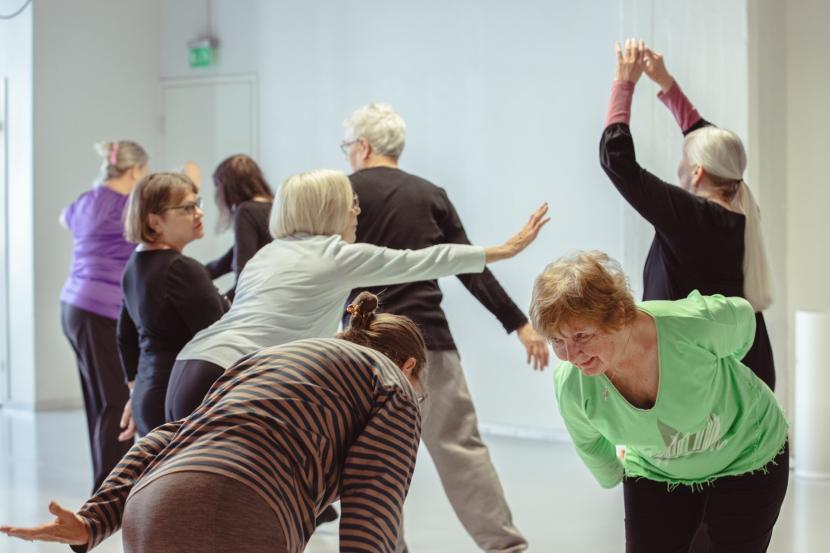 A group of elderly people dancing in a white studio